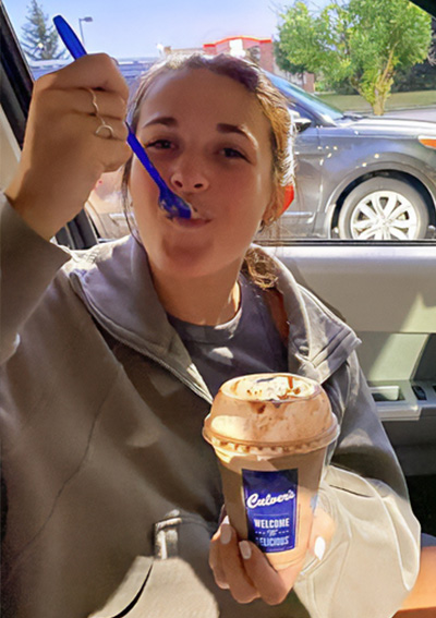 Girl smiling while taking a bite of a Concrete Mixer.